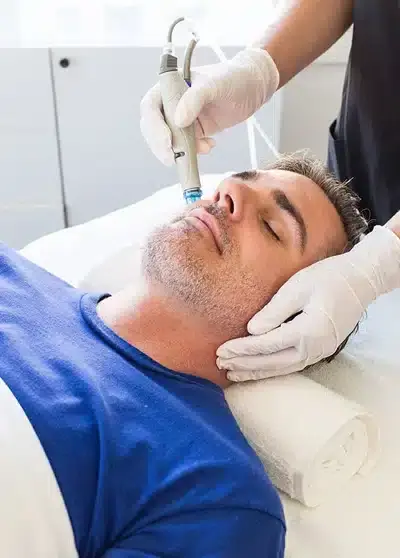 Mann erhält eine entspannende Mikrodermabrasionsbehandlung im Gesicht bei Behnaz's Beauty Bar