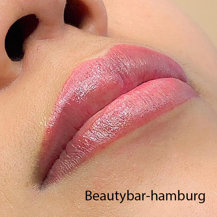 Nahaufnahme frisch Aquarell Lippen: Volle, rosafarbene Lippen mit glänzendem Finish zeigen das unmittelbare Ergebnis einer Pigmentierungsbehandlung. Beautybar-hamburg Wasserzeichen.